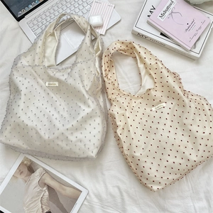 Detailed macro view of large organza tote bags with polka dots on soft white fabric