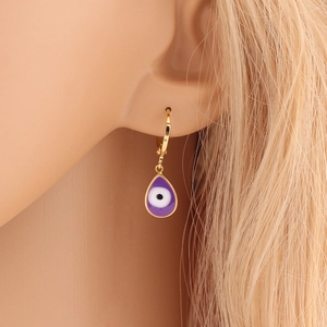 Close-up of gold teardrop evil eye earrings with purple and white enamel on ear