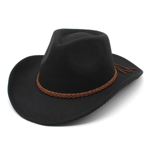 Détail du chapeau en laine noire avec bande tressée marron et pompon sur le côté