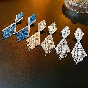 Makroaufnahme geometrischer Quastenohrringe in Blau, Gold und Silber mit Kristallen