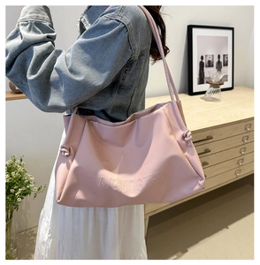 Detail shot of the embossed letter texture and knotted side on a pink leather tote bag