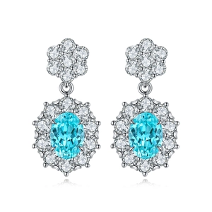 Macro shot of sky blue oval gemstone earrings with sparkling white petal halo and silver plating