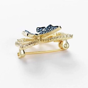 Close-up of golden bow brooch with blue enamel butterfly and sparkling crystals
