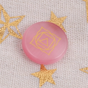 Macro di pietra chakra in opale rosa con simbolo della radice dorato su tessuto