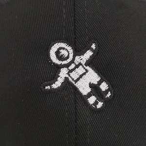 Close-up of white astronaut embroidery on black cotton twill texture of the baseball cap