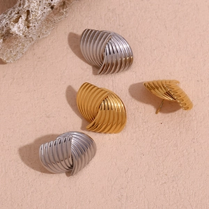 Detailed view of geometric shell-textured stud earrings in gold and silver finishes
