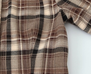 Vue détaillée du tissu en laine à carreaux épais et des coutures soignées de la chemise
