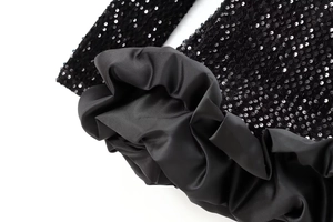 Vue macro détaillée du tissu à paillettes noires et volants satinés sur la robe courte