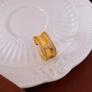 Dettaglio macro dell'anello largo placcato oro con trama spazzolata e intarsio di zirconi