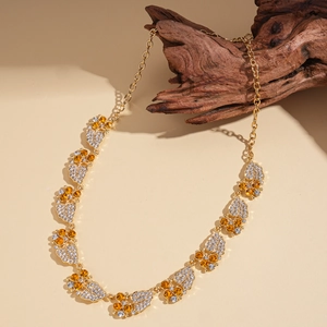 Detailopname van gouden bladhangers met fonkelende kristallen op een gelaagde ketting