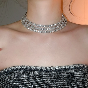 Close-up of triple-layer faux pearl and rhinestone bow necklace on a model neckline