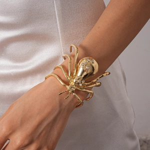 Detailed view of a gold spider cuff bracelet with sparkling rhinestones on model's wrist