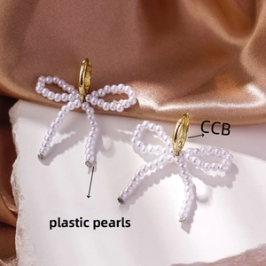 Macro detail of French bow earrings with flowing pearls and golden CCB loops