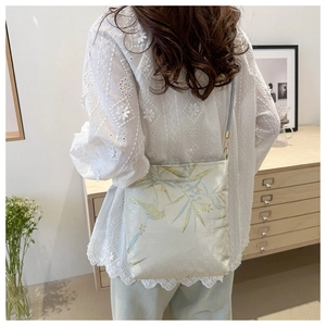Detail of embroidered bamboo and bird motifs on a beige Chinese style bucket bag