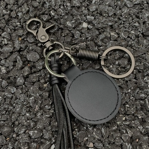 Handmade black leather braided rope keychain with metal spring hook on stone background