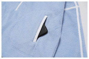 Macro detail of side pocket with white trim on a light blue fleece sports jacket