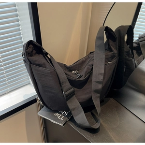 Detail view of the black crescent crossbody bag with adjustable strap and metallic zipper