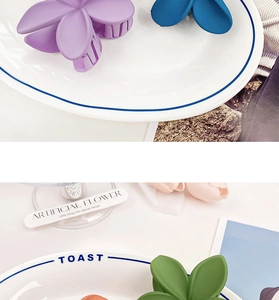 Matte finish frangipani flower hair claws in assorted pastel colors on a ceramic tray
