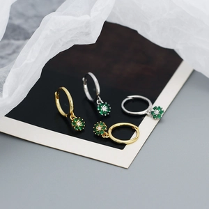 Macro detail of gold and silver flower hoop earrings with green zircon flower pendants