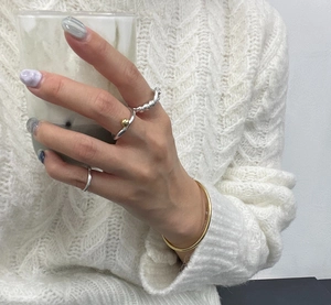 Detailed view of layered knotted 925 sterling silver rings and a slim gold bracelet