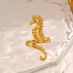 Gold seahorse ring with detailed scales on a wave texture glass background
