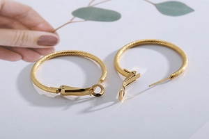 Close-up of golden hoop earrings featuring intricate twisted rope texture and clasp detail