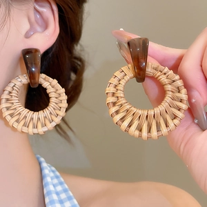 Detail of round woven rattan earrings with tortoiseshell resin links in boho style