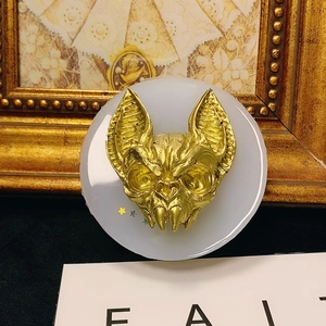 Detailed view of a gothic golden bat head sculpture with metallic finish on a round base