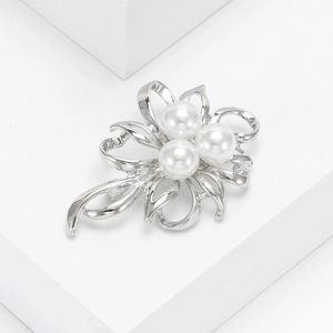 Elegant silver flower brooch with pearls on a white podium, refined floral accessory