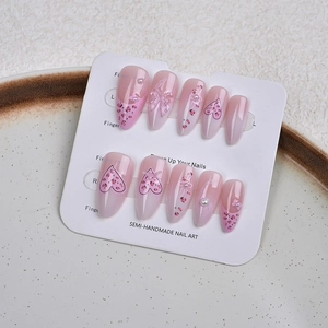 Détail de faux ongles amande avec nœuds 3D, cœurs léopard et décorations de perles