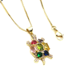 Gold turtle necklace featuring colorful zircon stones and box chain on white background