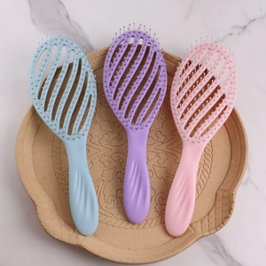 Three vented hair brushes in blue, purple, and pink on a decorative ceramic tray