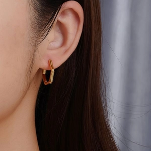 Boucles d'oreilles tendance en acier inoxydable doré 18 carats portées par un mannequin