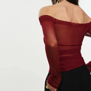 Detail of burgundy off-shoulder top featuring sheer mesh sleeves and back ruching