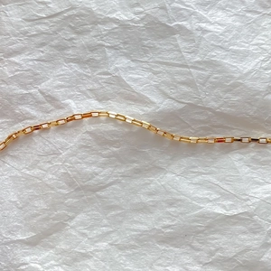 Detailed close-up showing the fine links of a gold 14K plated titanium steel box chain necklace