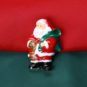 Détail de la broche Père Noël avec émail et bordure dorée sur tissu festif