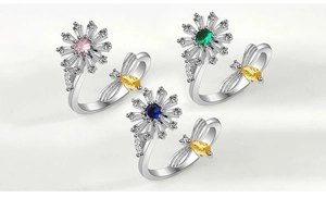 Detailed macro view of rotating daisy and bee rings with vibrant colorful gemstones