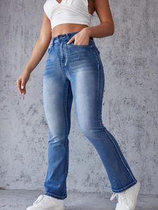 Detail of high waisted distressed blue jeans showing slim fit cut and vintage wash finish