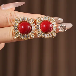 Vintage style gold-plated earrings with large red gemstone and zircon accents on hand