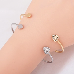 Close-up of gold and silver heart-shaped open bracelets with sparkling zircon stones