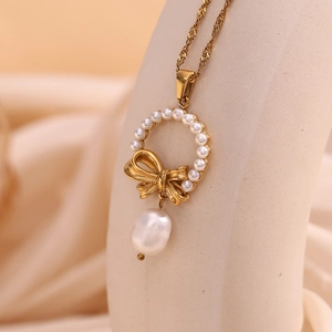 Detail of 18K gold bow necklace featuring small pearls and baroque pearl pendant