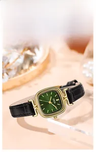 Detail of square gold watch with green sunray dial and black leather strap on display