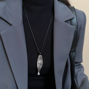 Close-up of leaf pendant necklace with textured silver finish and drop zircon stone detail
