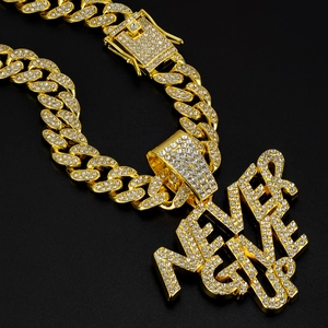 Macro detail of gold Cuban chain and HIVE pendant paved with sparkling crystals