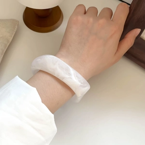 Close-up of white marble resin bangle with elegant cloud texture worn on a wrist