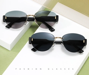 Close-up of rimless oval sunglasses with gold metal bridge and gradient black lenses