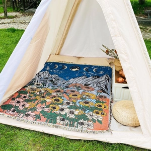 Detail of bohemian outdoor blanket with sunflower and moon phase woven pattern and tassels