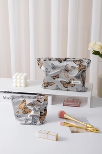 Detail of silver silk makeup bags with yellow butterfly jacquard and golden ring zipper