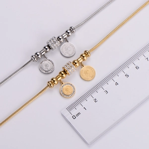 Detail view of gold and silver snake chain necklaces with Elizabeth coin and crystal charm