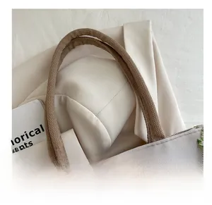 Detailed view of canvas tote bag featuring floral bird embroidery and woven rope handles